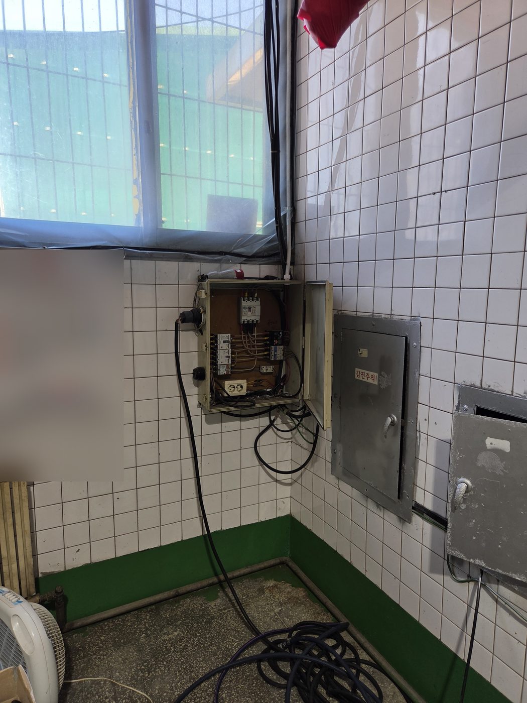 문이 열린 분전반과 바닥에 늘어진 전선